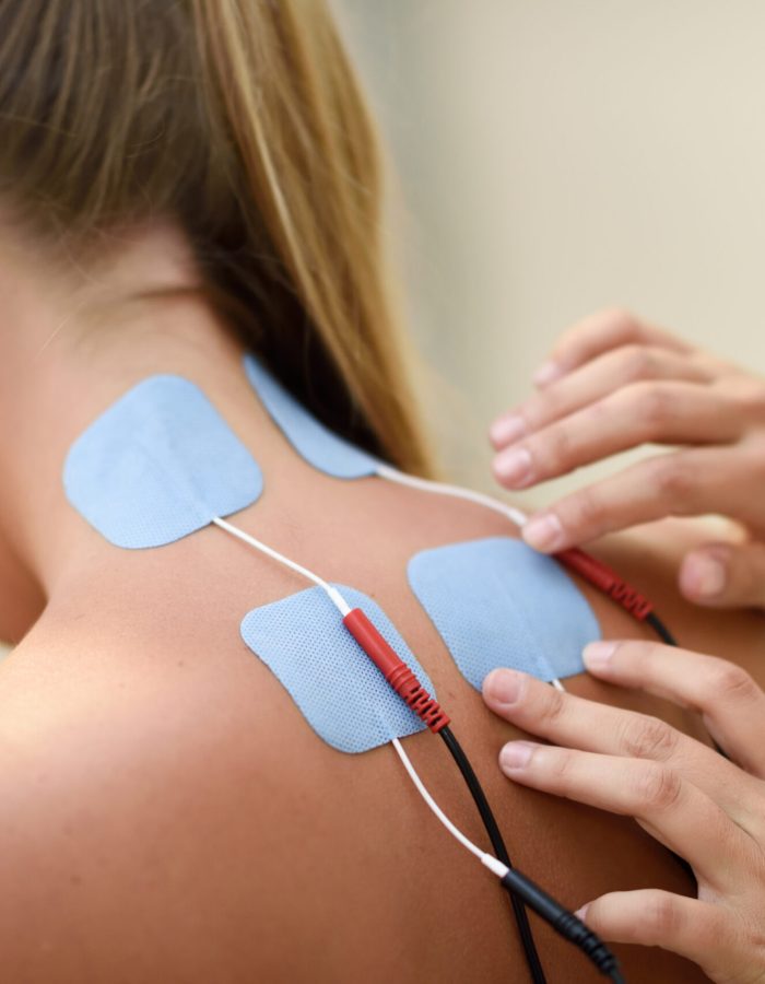 Electro stimulation in physical therapy to a young woman. Medical check at the shoulder in a physiotherapy center.