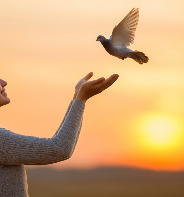 A woman is holding a bird in her hands. The bird is white and flying in the sky