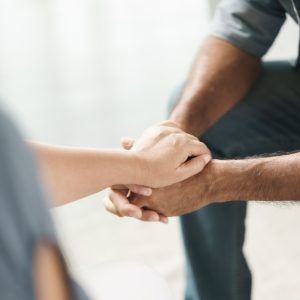 Female friend or family sitting and hold hands during cheer up to mental depress man, Psychologist provides mental aid to patient. PTSD Mental health concept