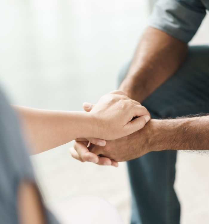 Female friend or family sitting and hold hands during cheer up to mental depress man, Psychologist provides mental aid to patient. PTSD Mental health concept