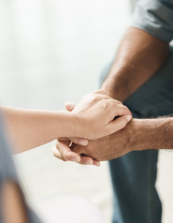 Female friend or family sitting and hold hands during cheer up to mental depress man, Psychologist provides mental aid to patient. PTSD Mental health concept