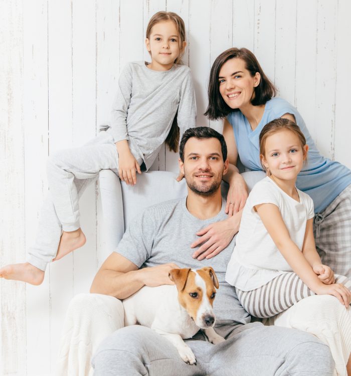 Friendly family of four memebers: cheerful European brunette female, her husband, two daughters and favourite pet, have good relationships, support each other. Affectionate parents with children