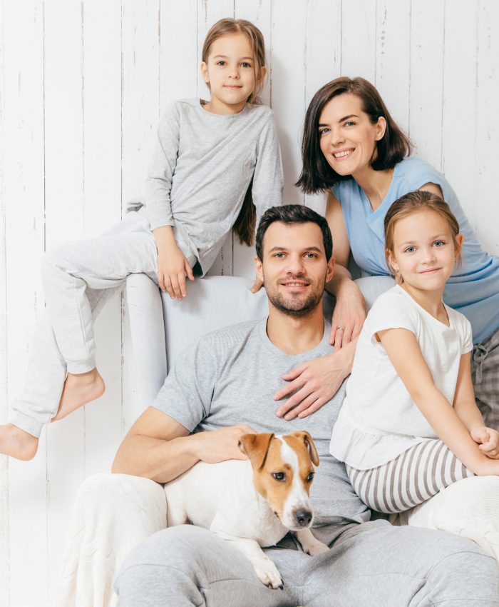 Friendly family of four memebers: cheerful European brunette female, her husband, two daughters and favourite pet, have good relationships, support each other. Affectionate parents with children