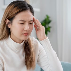 Headache, female having migraine pain, bad health, Asian woman feeling stress and headache, Office syndrome, sad tired touching forehead having migraine or depression, irritated girl, sadness grief