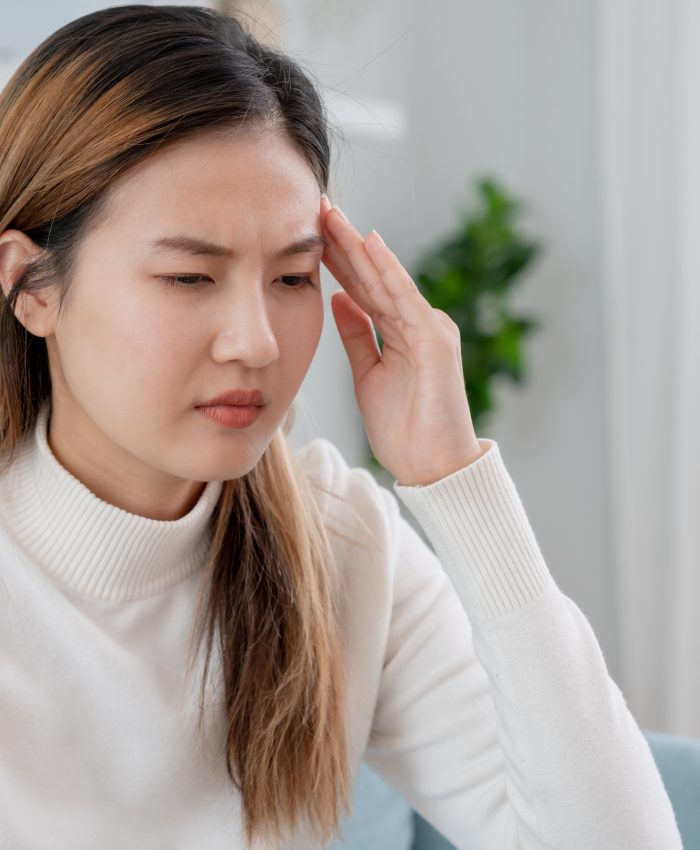 Headache, female having migraine pain, bad health, Asian woman feeling stress and headache, Office syndrome, sad tired touching forehead having migraine or depression, irritated girl, sadness grief
