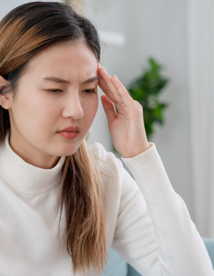 Headache, female having migraine pain, bad health, Asian woman feeling stress and headache, Office syndrome, sad tired touching forehead having migraine or depression, irritated girl, sadness grief