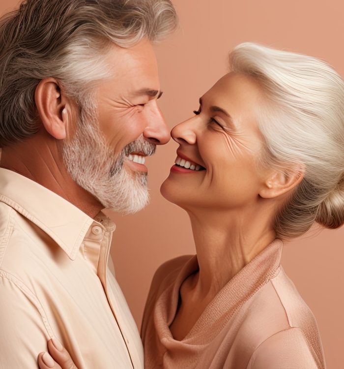 Waist up portrait of happy elderly couple embracing and gazing at each other on beige backdrop