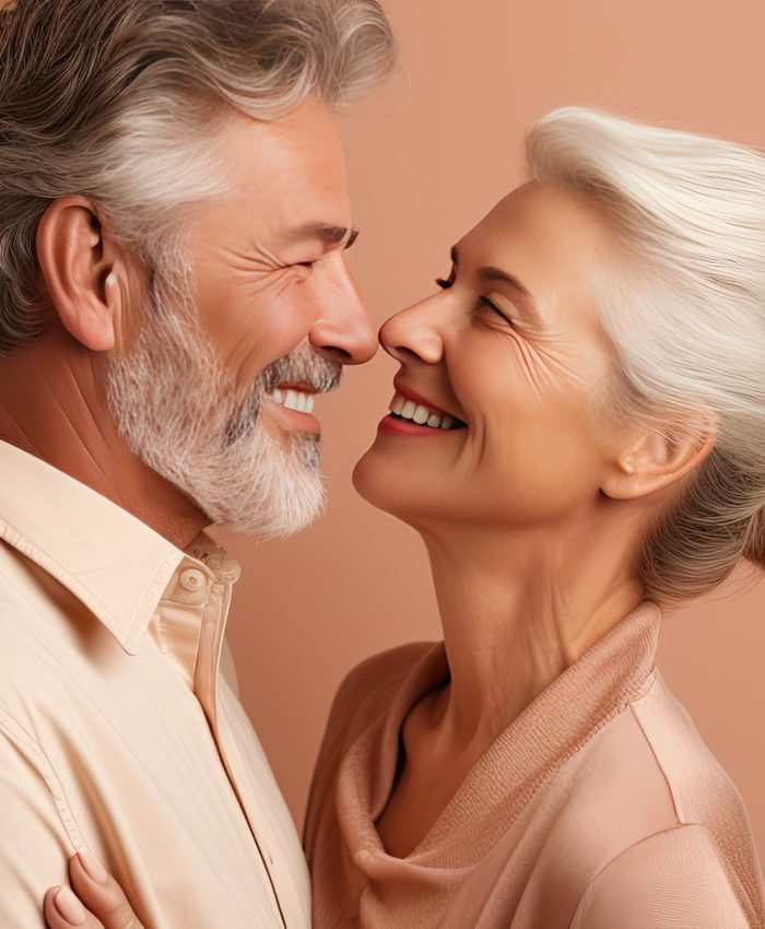 Waist up portrait of happy elderly couple embracing and gazing at each other on beige backdrop